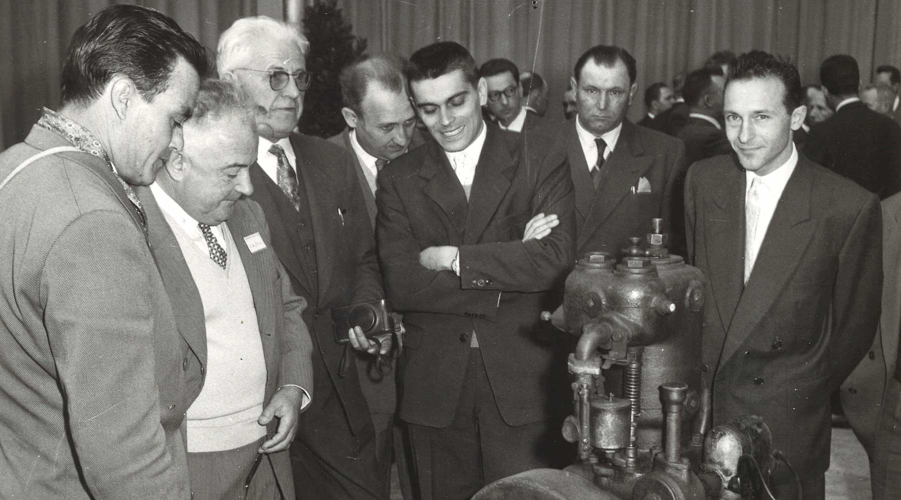 Old photo of a group of people around a Moteurs Baudouin engine.
